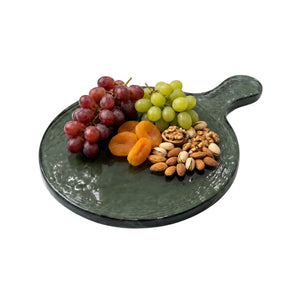Green glass platter with grapes, apricots, and nuts on a white background