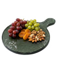 Green glass platter with grapes, apricots, and nuts on a white background