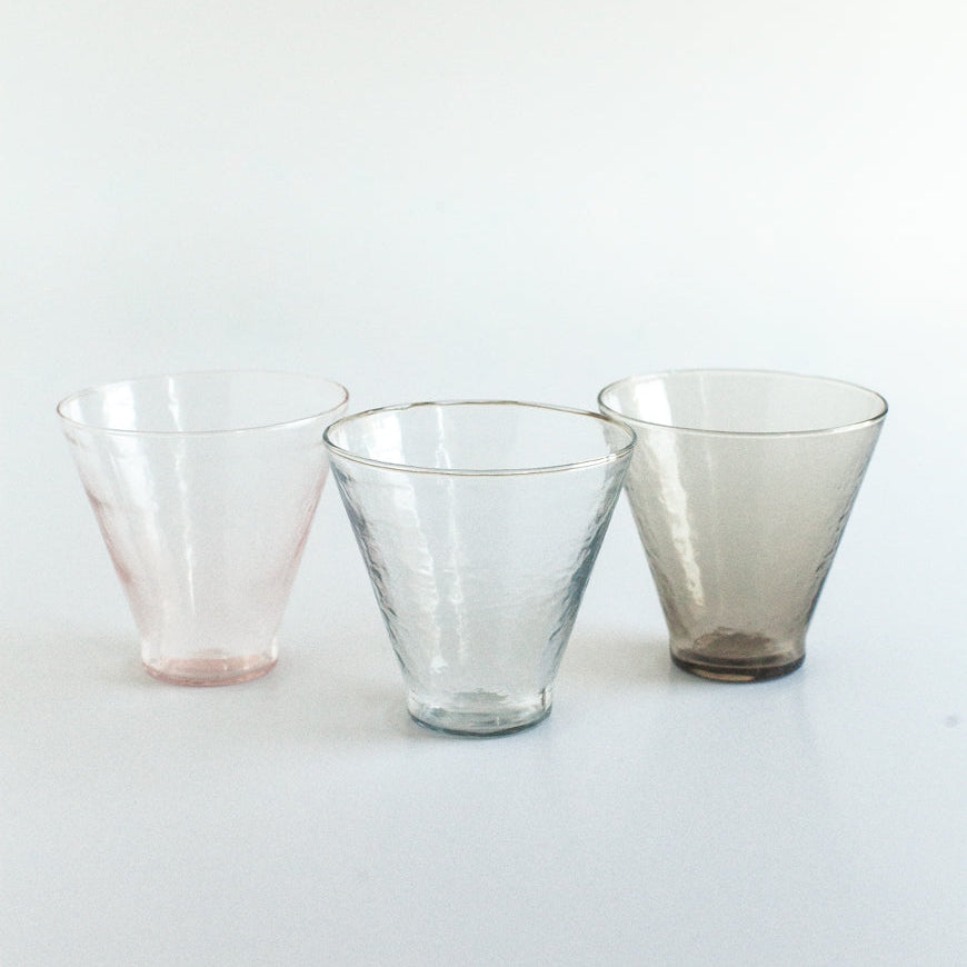 Three glass tumblers of different colors on a white background