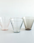 Three glass tumblers of different colors on a white background