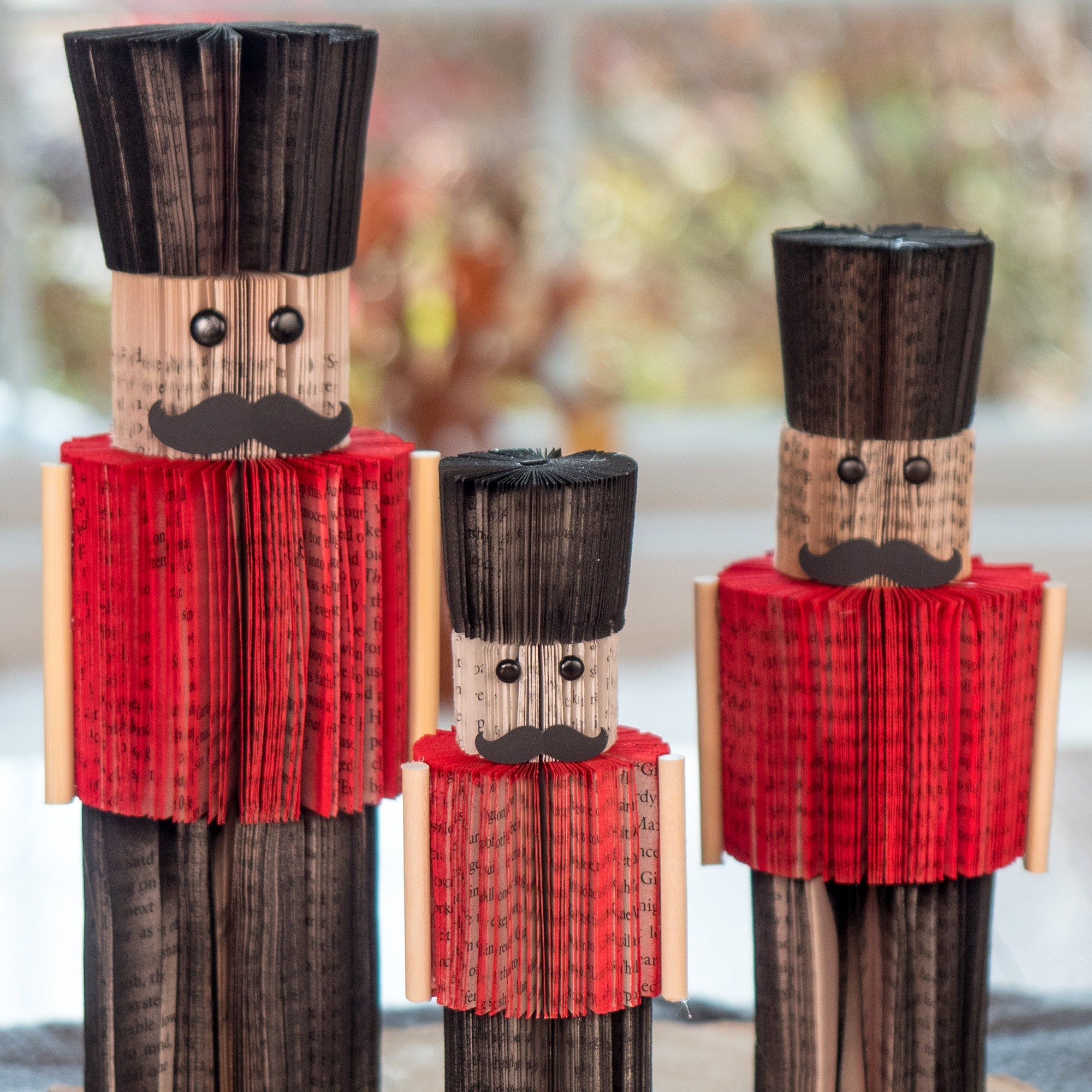 Three wooden nutcrackers with red outfits and black hats on a blurred background