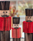 Three wooden nutcrackers with red outfits and black hats on a blurred background