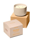 Candle in a beige container with a matching box on a white background