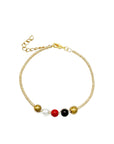 A gold-colored bangle bracelet featuring multicolored beads in a pattern of gold, black, red, and white, with a lobster clasp and an extender chain.