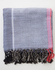 Textured bath towel with striped pattern and frayed edges on a white background