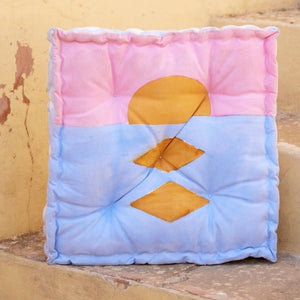 Colorful floor cushion with geometric patterns on a textured surface