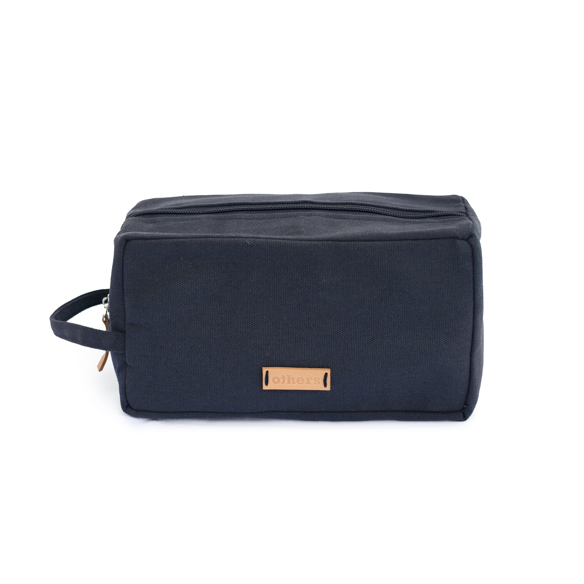 Navy blue toiletry bag with a brown leather patch on a white background