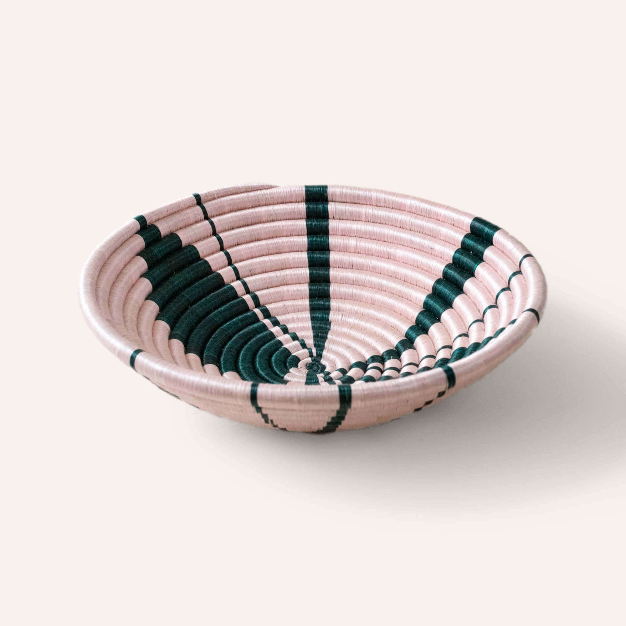Woven bowl with pink and green pattern on a white background
