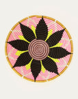 Decorative woven plate with pink, black, and yellow pattern on a white background