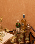 Bar cart with cocktail ingredients and tools against a brown wall