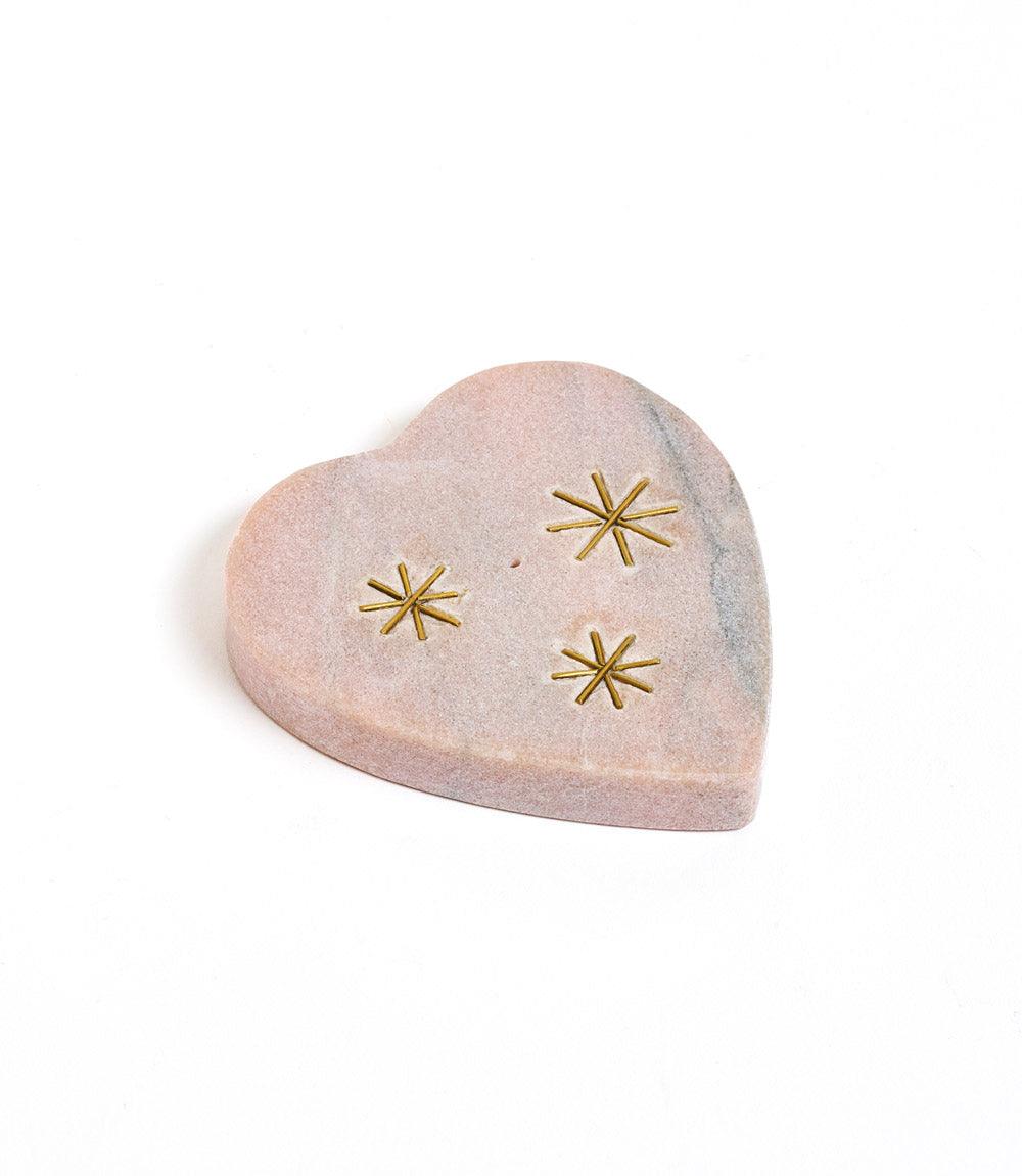 Heart-shaped marble incense holder with gold star designs on a white background