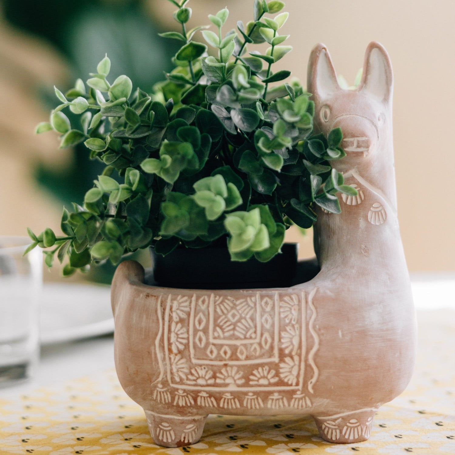 Ceramic cat-shaped planter with a green plant on a table
