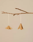 Two brass ornaments hanging from a branch against a beige background