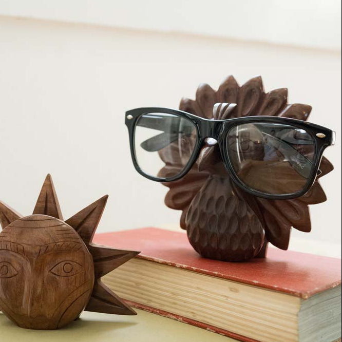 Wooden animal-shaped glasses holders on books with a blurred background