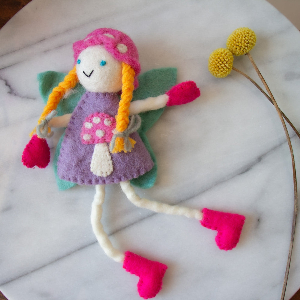 Blonde mushroom bonnet tooth fairy pillow with pink boots and a purple dress displayed on a light surface.
