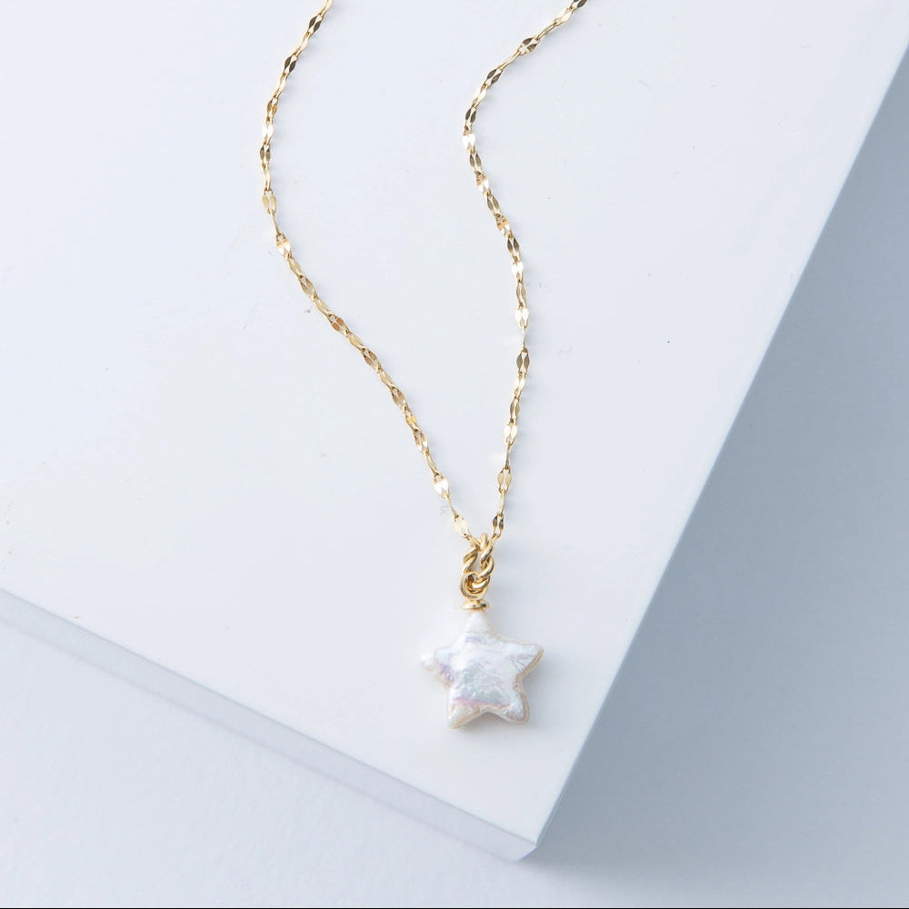 Gold necklace with a star-shaped pendant on a light background