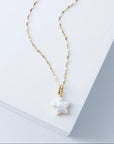 Gold necklace with a star-shaped pendant on a light background