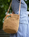 Person wearing a blue striped dress with a woven basket bag outdoors.