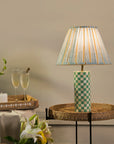 Decorative lamp with a checkered base on a table, accompanied by glasses of champagne and a plant.