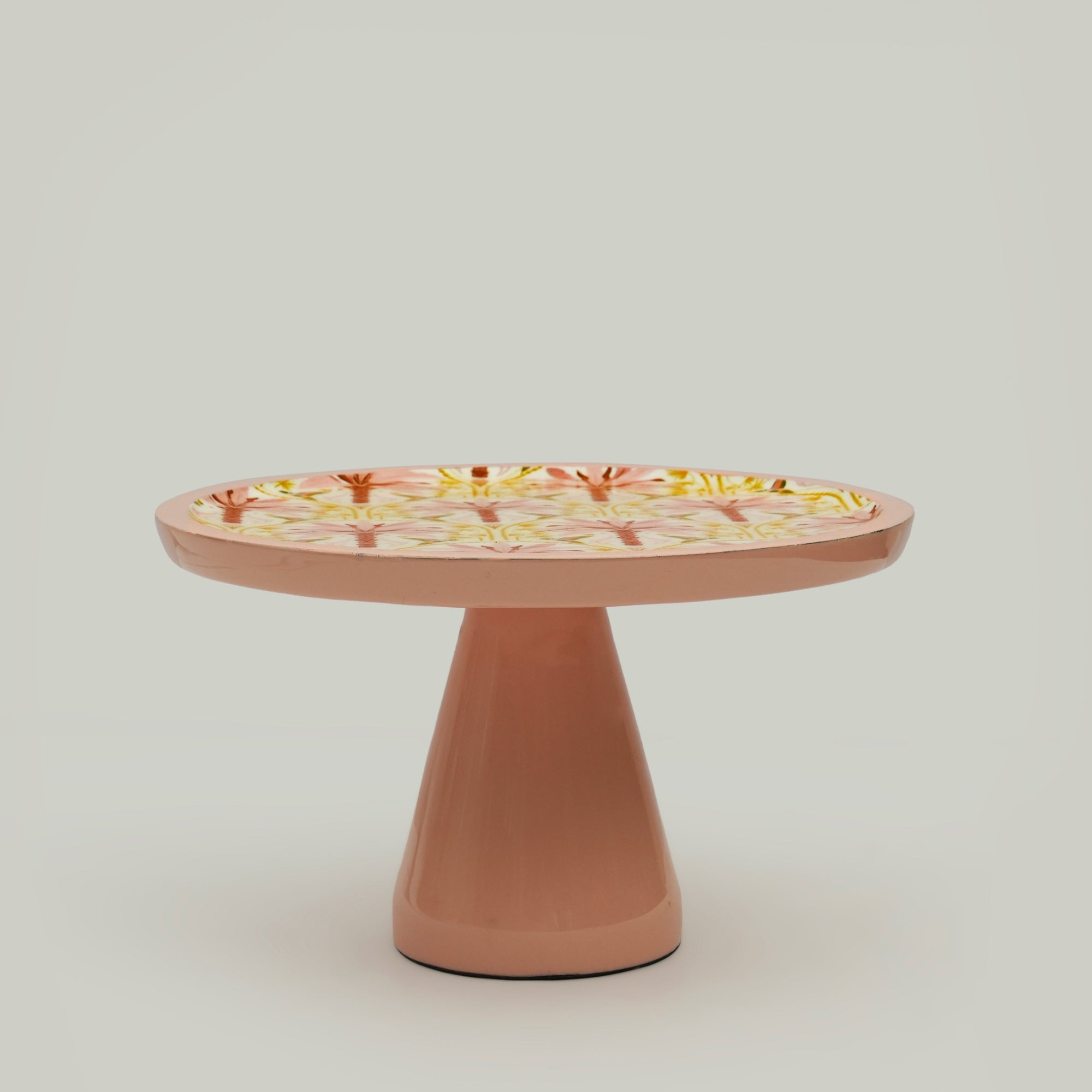 Wooden cake stand with floral pattern on a plain background