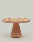 Wooden cake stand with floral pattern on a plain background