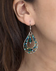 Teardrop-shaped earring with colorful beads worn by a person.