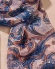 Close-up of a patterned fabric scarf with blue and orange designs on a beige background