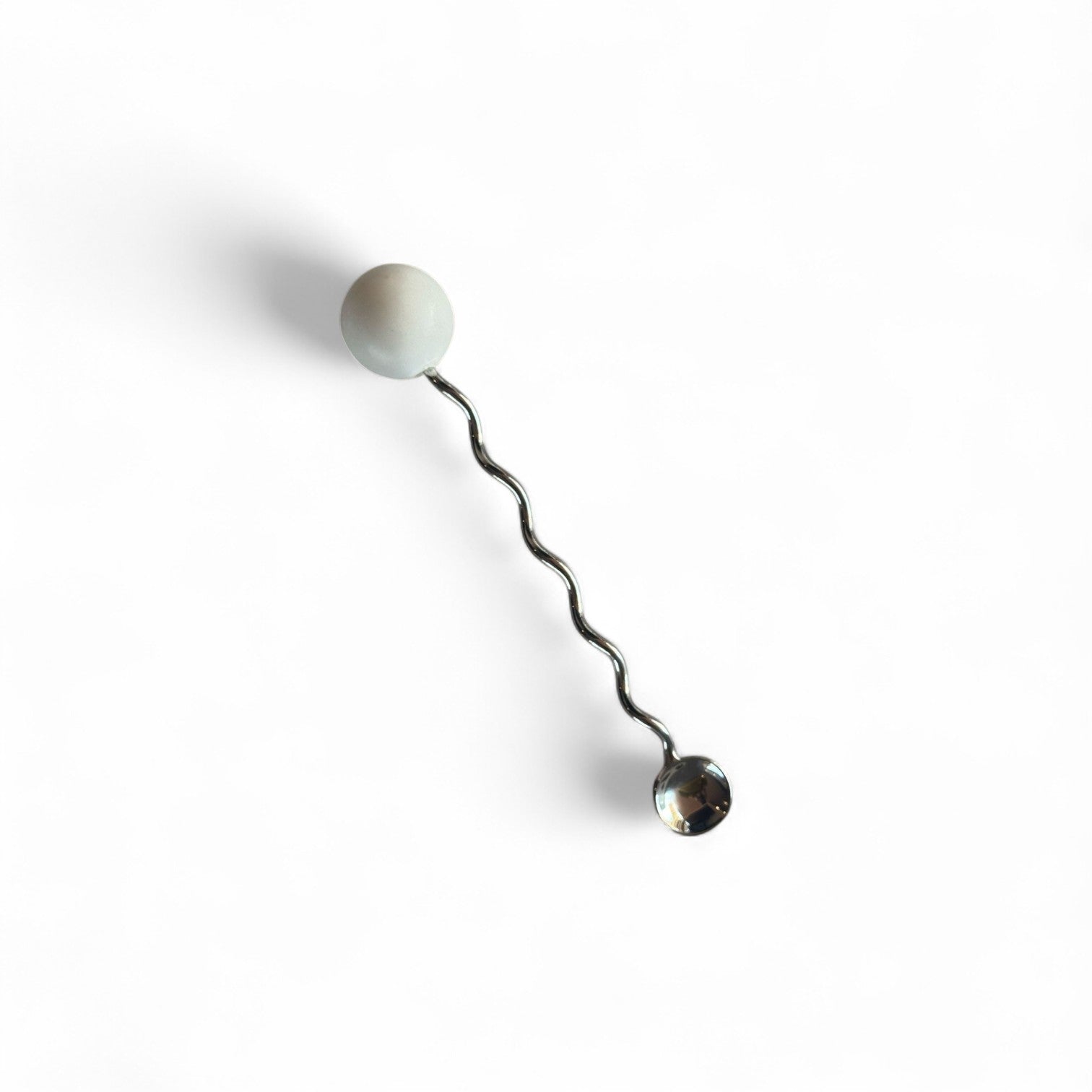Metallic drink stirrer with a marble spherical end on a white background