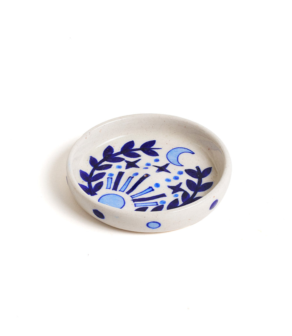 A round ceramic incense holder with hand painted blue floral patterns on a white background.