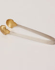 Gold and silver tongs on a light beige background