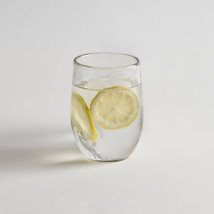 A clear glass with water and lemon slices on a white background, resembling one of the glasses in the set.
