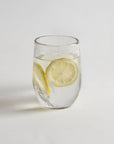 A clear glass with water and lemon slices on a white background, resembling one of the glasses in the set.