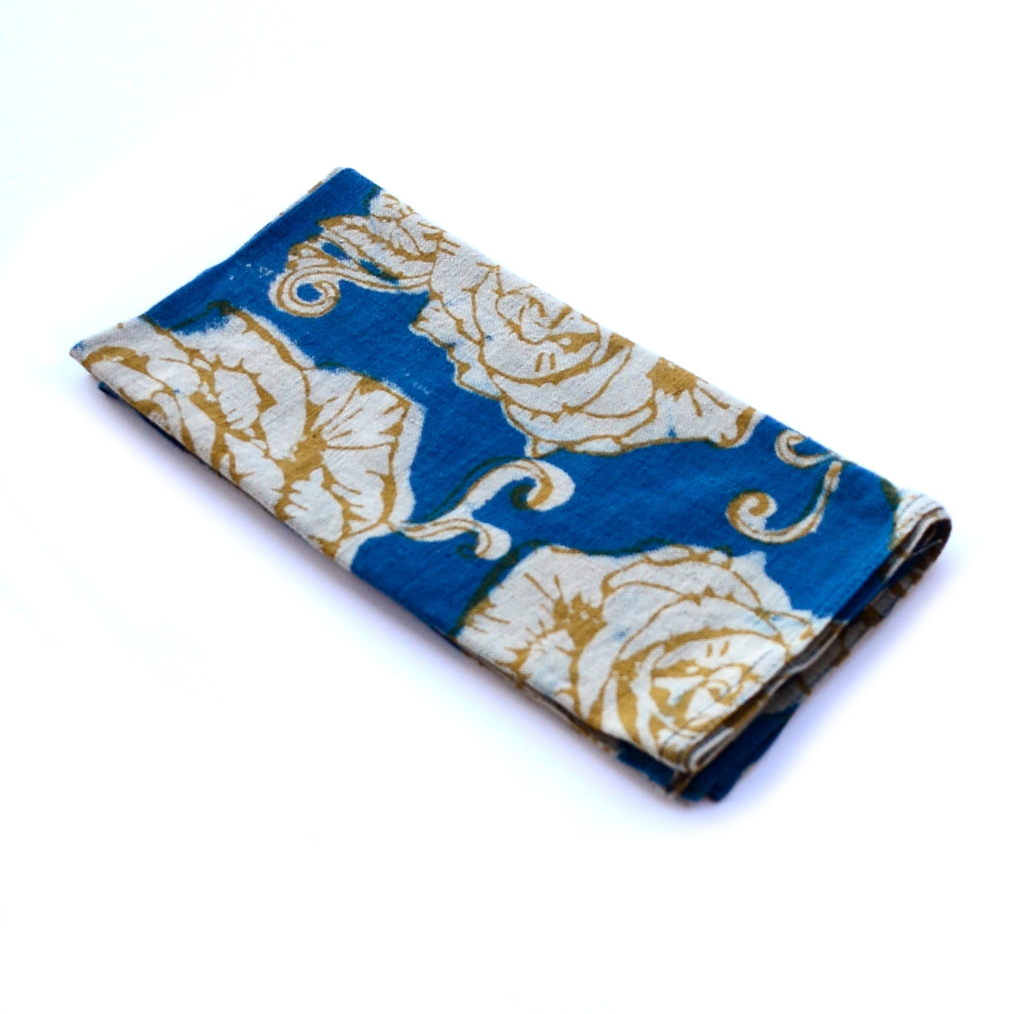 Folded napkin with gold floral pattern against a white background