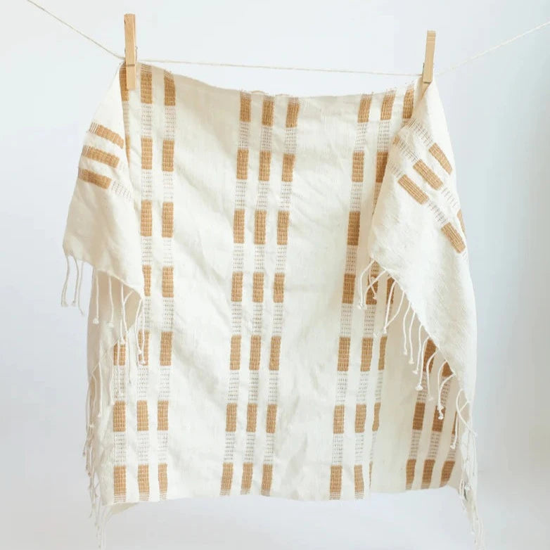Plaid hand towel with white and brown pattern hanging on a clothesline against a white background
