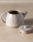 Ceramic teapot with geometric design on a beige background