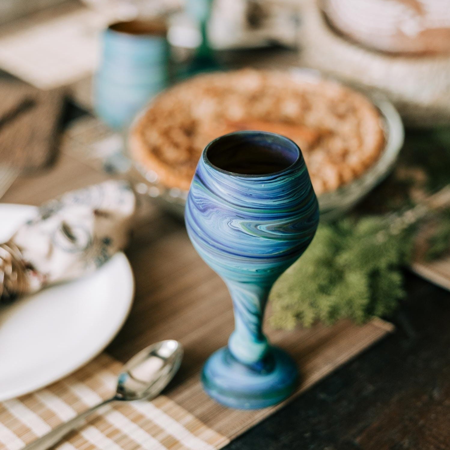 Blue swirled goblet on a wooden table with a blurred background