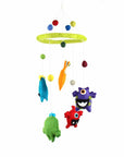 A colorful felt mobile featuring a variety of monster shapes in green, blue, and purple, with a yellow circle at the top and a series of dangling balls.