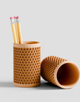 Pencil holder with honeycomb pattern containing pencils on a light gray background