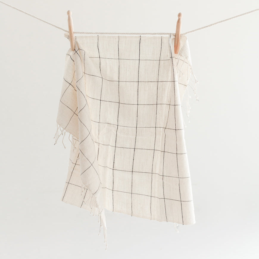 Windowpane checkered hand towel hanging on a clothesline against a white background