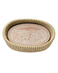 Round woven bread basket with a decorative ceramic plate inside on a white background